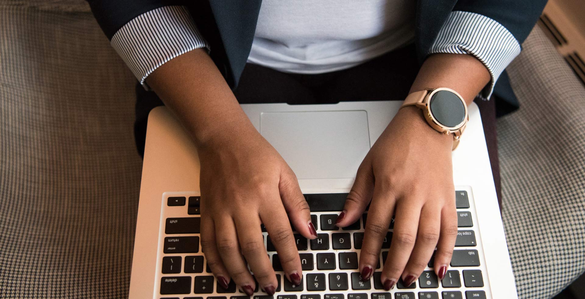 Close-up of a woman's hands typing on a laptop keyboard.