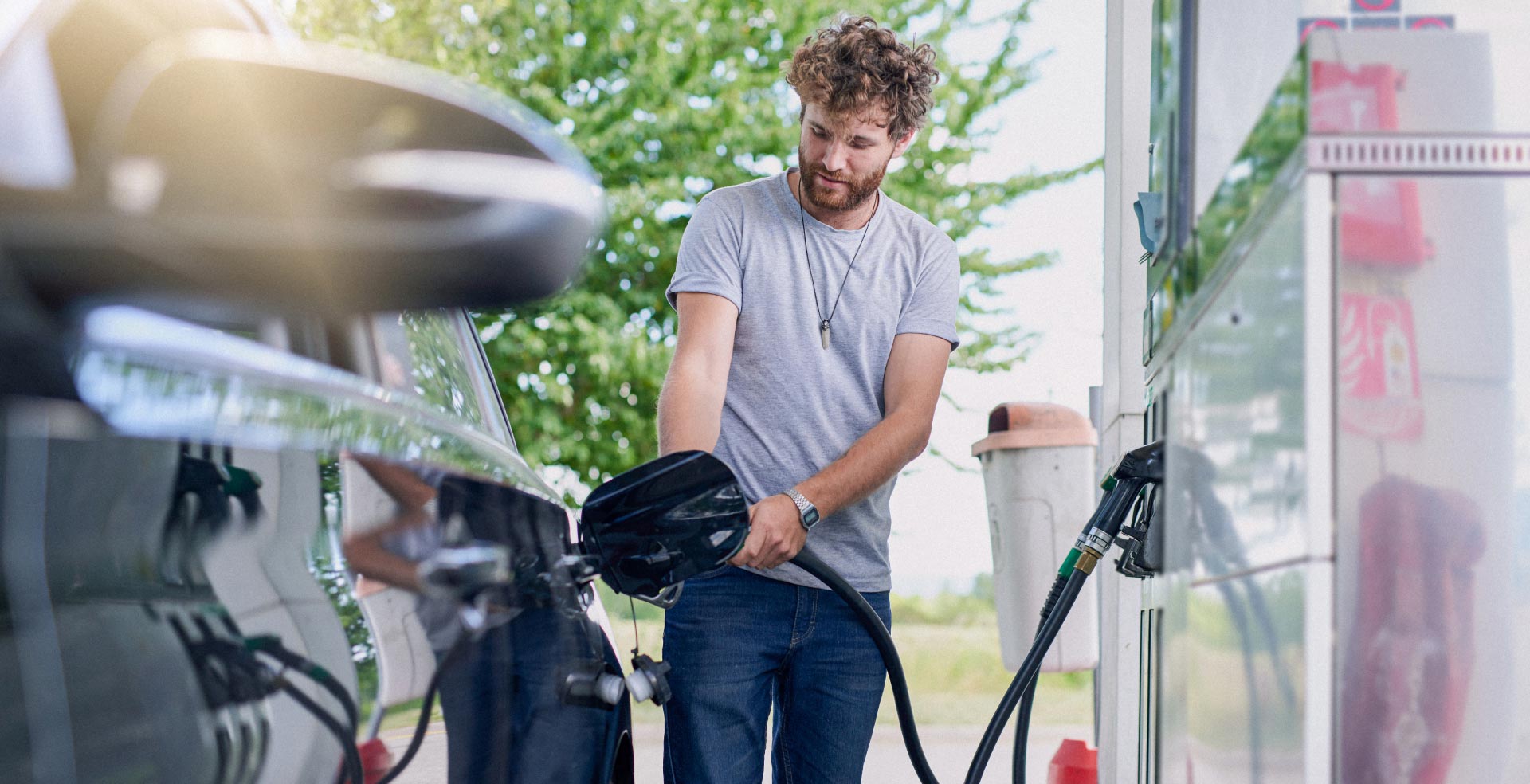 A man pumping gas into his car at a gas station.