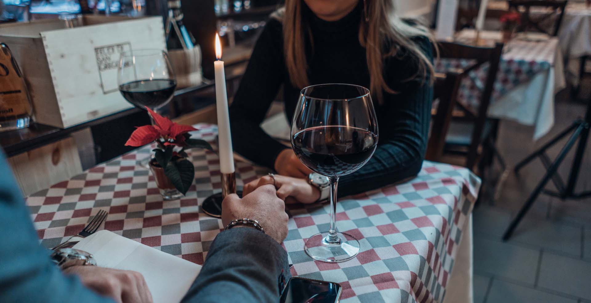 A man and a woman holding hands at a restaurant.