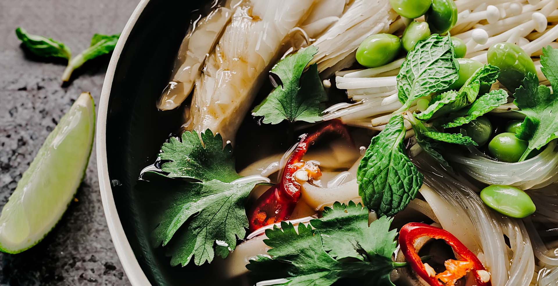 A salad bowl with various vegetables on a black table.