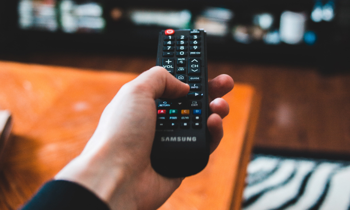 Close-up of a man's hand holding a Samsung T.V remote control.