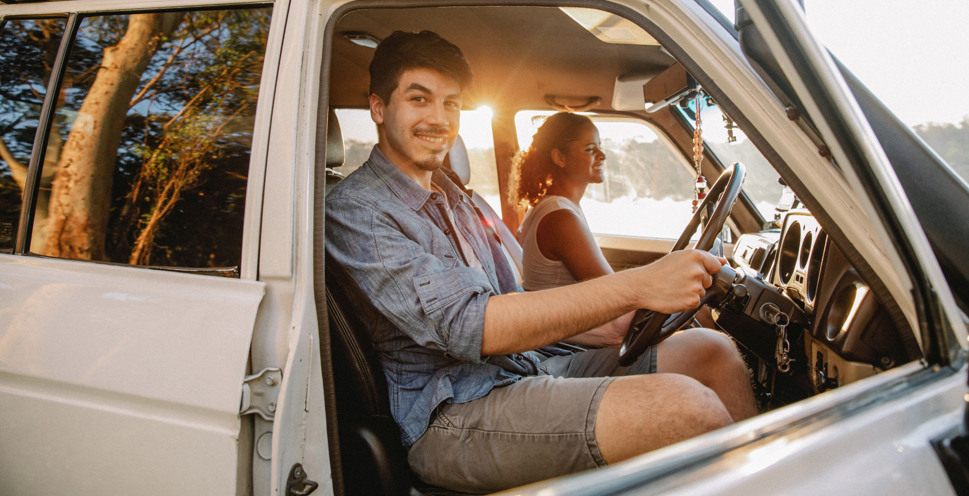 A man and a woman sitting in a car smiling.