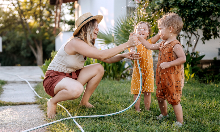 A mother playing in a backyard with her two children.