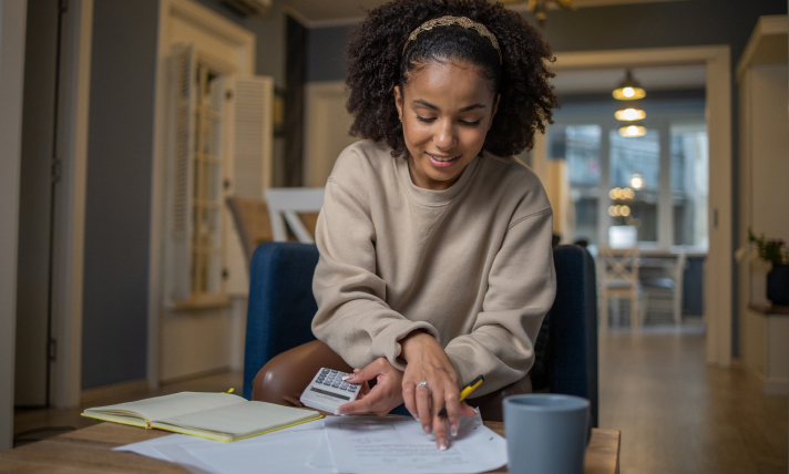 A woman sitting at a table writing on a piece of paper.