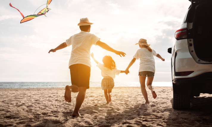 A man, a woman, and a little girl running happily on a beach.