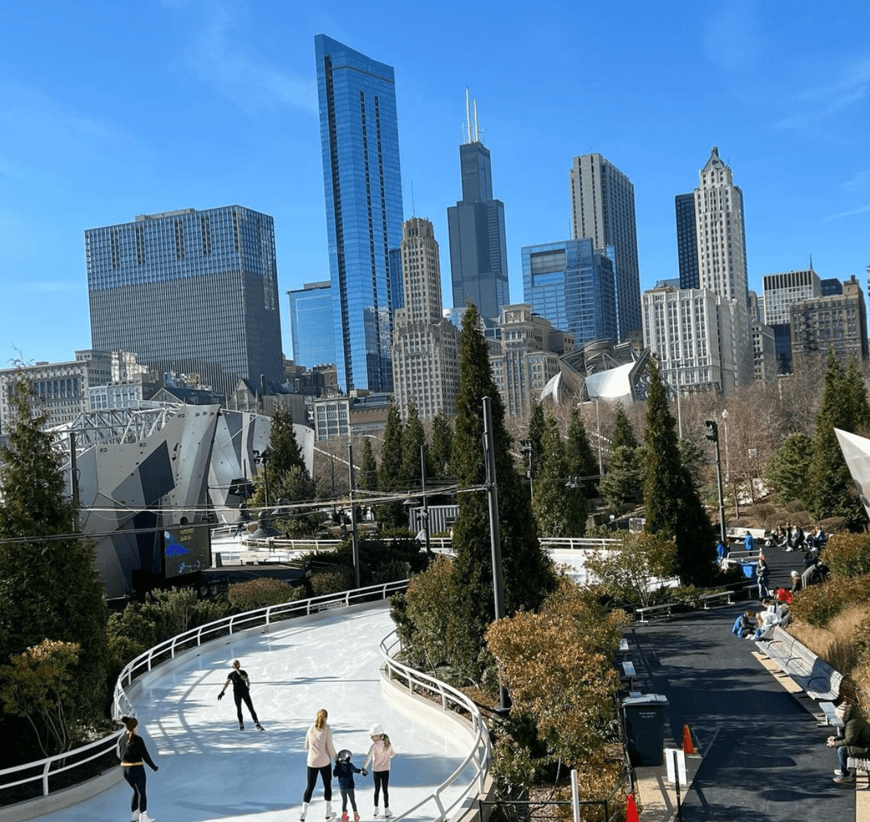 Four people ice skating on the Maggie Daley park ice ribbon with the Chicago skyline in the background