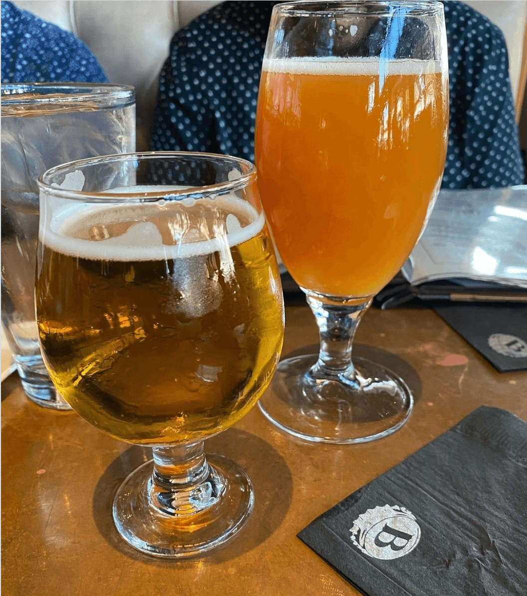 Two beers sitting on a table.