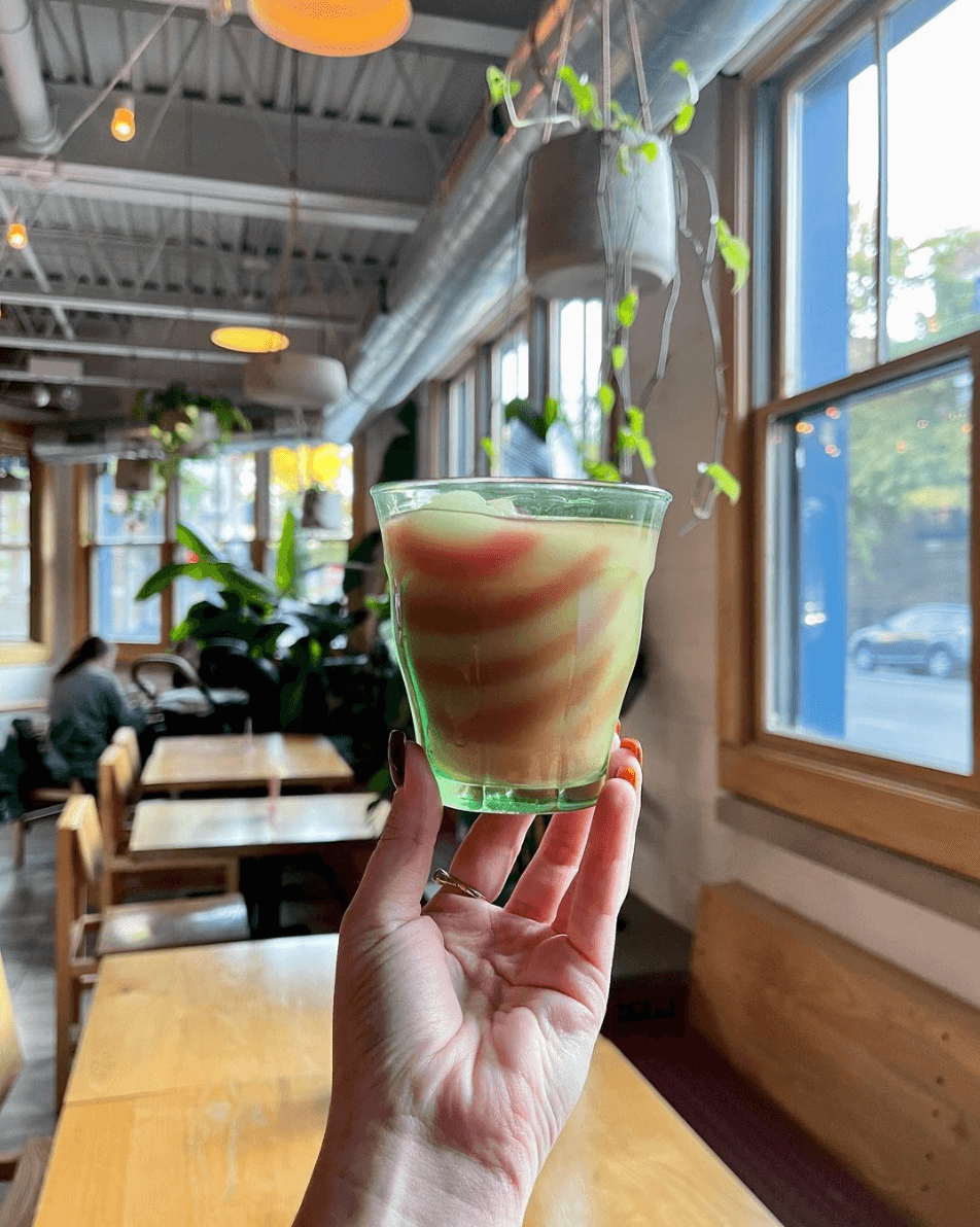 Hand holding up a striped red and yellow margarita in a glass.